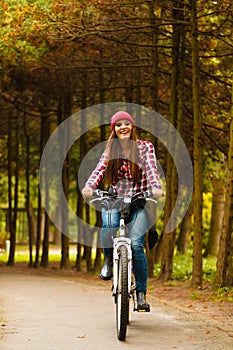 Girl relaxing in autumnal park with bicycle.