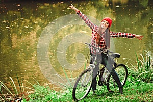 Girl relaxing in autumnal park with bicycle.