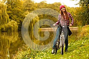 Girl relaxing in autumnal park with bicycle.