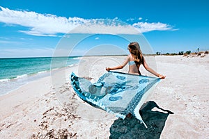 Girl holding pareo on the beach photo