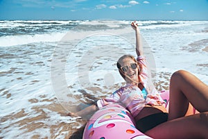 Girl relaxing on donut lilo on the beach