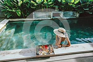 Girl relaxing and eating fruits in the pool on luxury villa in Bali