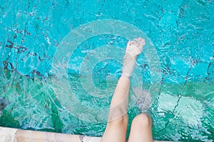 girl relaxing feet with water in the pool.