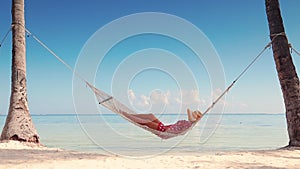 Girl relaxing in a hammock on tropical island beach. Summer vacation