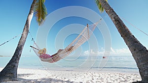 Girl relaxing in a hammock on tropical island beach. Summer vacation in Punta Cana, Dominican Republic