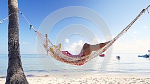 Girl relaxing in a hammock on tropical island beach. Summer vacation in Punta Cana, Dominican Republic