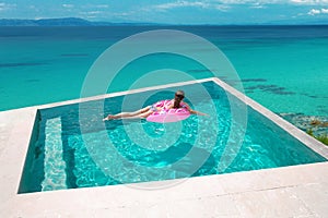 girl relaxing on inflatable pink donut in the infinity swim