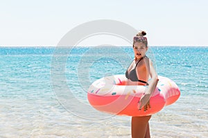 Girl relaxing with inflatable ring on the beach. shocked or surprised girl in the cold sea. Summer holidays and vacation concept