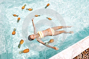 Girl relaxing in pool with pineapples