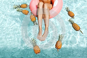Girl relaxing in pool with pineapples