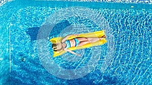 Girl relaxing in swimming pool, child swims on inflatable mattress and has fun in water on family vacation