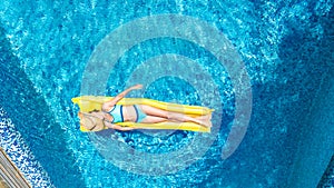 Girl relaxing in swimming pool, child swims on inflatable mattress and has fun in water on family vacation