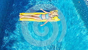 Girl relaxing in swimming pool, child swims on inflatable mattress and has fun in water on family vacation, tropical holiday