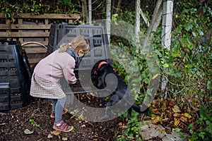 Girl removing compost from a composter in the garden. Concept of composting and sustainable organic gardening.