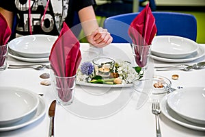 A girl in a restaurant sits at a table with empty plates and orders food