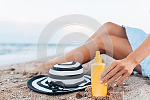 Girl resting on the beach, beautiful tanned legs against the blue sea, jar of cream