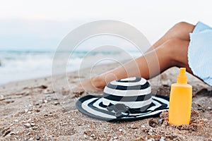 Girl resting on the beach, beautiful tanned legs against the blue sea, jar of cream