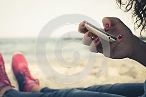 Girl resting on the beach and using a mobile phone