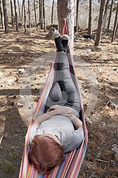 girl resting in a colorful hammock in the woods