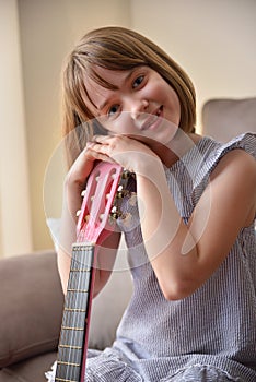 Girl resting on the headstock of a guitar smiling