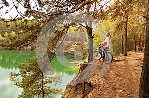 Girl resting on the shore of a mountain lake after walking a bike