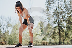 Girl resting after sprinting on race track in the park. Exhausted female runner concept.