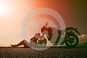 Girl resting in the sun sun leaning against the wheel of his mot