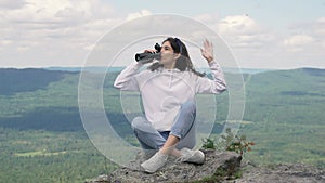 A girl is resting on the top of a mountain after a hike and drinking hot tea