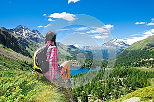 Girl resting during a trek in the mountains watching the view over a lake