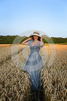 Vertical portrait of a young pretty woman-coquette against the background of a wheat field