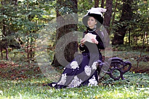 Girl in retro dress past century read letter on bench