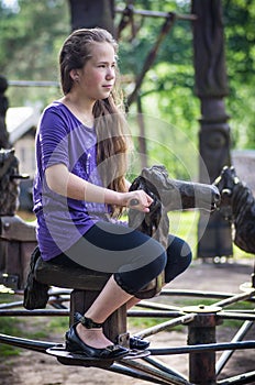 A girl ridding on a wooden horse