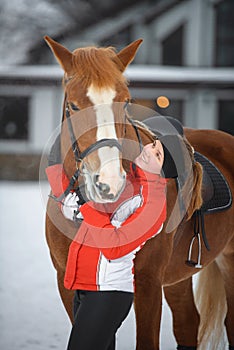 A girl rider trains riding on her horse in the snowy winter