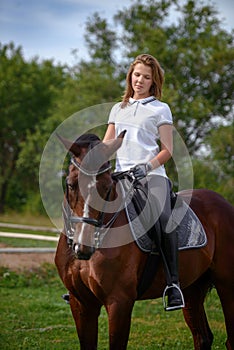 A girl rider trains riding a horse on a spring day