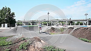 A girl rides a 2-wheeled scooter on the sports slides in the park in the early summer morning. concept of sports child development