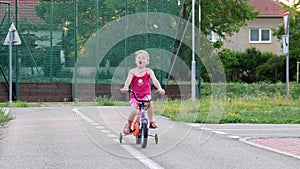 Girl rides the bike at playground traffic. Little girl on bike in the summer. Slow and revers motion