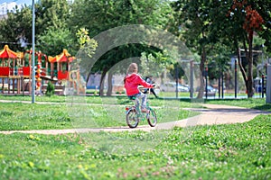 Girl rides a child`s bike in a summer park
