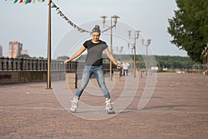 A girl rides roller skates in a city Park in summer