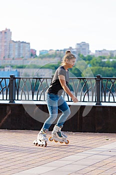 A girl rides roller skates in a city Park in summer