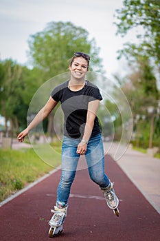 A girl rides roller skates in a city Park in summer