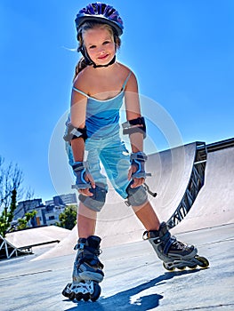 Girl rides on roller skates in skatepark.