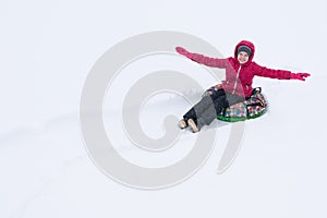 The girl rides on a round inflatable sled in the white snow, leaves traces