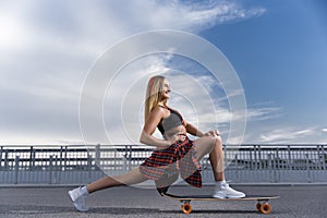 Girl rides a skate against the sky
