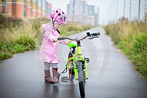 Girl rides a small Bicycle on a wet road