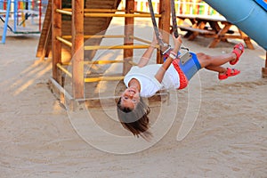 The girl rides on a swing in the playground.