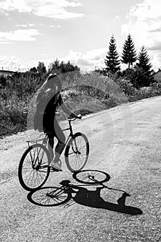 Girl riding a bicycle on a road on a sunny summer day, vacation