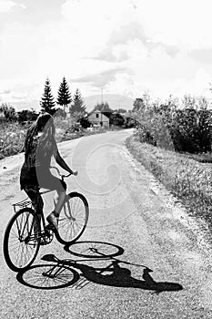 Girl riding a bicycle on a road on a sunny summer day, vacation