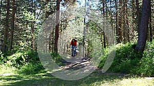 girl riding a bike in the forest on a dirt road