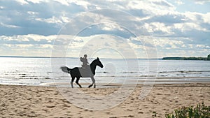 Girl riding a horse on coastline at the beach in early morning