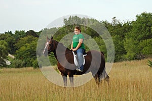 Girl riding horse in field